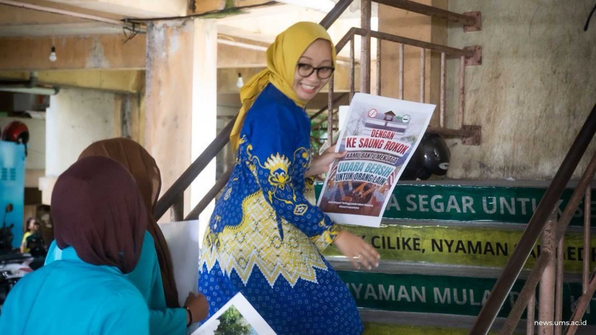 Nieldya membawa poster hasil dengan pesan nudging menapaki anak tangga dengan sticker pesan nudging untuk Rusunawa